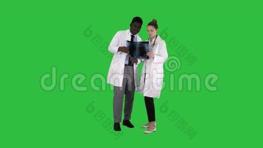 年轻的女医生和美国黑人医生看着绿色屏幕上肺部的x射线照片，ChromaKey。